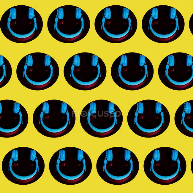 Vue du dessus des écouteurs sans fil placés sur des cercles et formant un motif sans couture sur fond jaune — Photo de stock