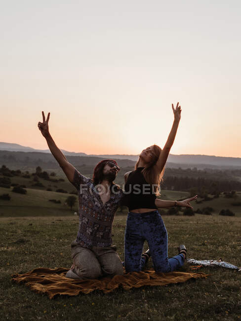Coppia con le braccia alzate nella natura mentre il sole tramonta in montagna — Foto stock