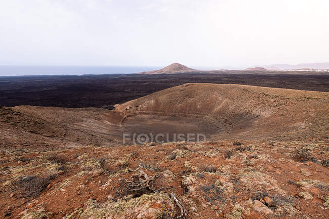 Vue pittoresque du cratère du volcan Caldereta contre les montagnes et la mer sous un ciel clair à Lanzarote Îles Canaries Espagne — Photo de stock