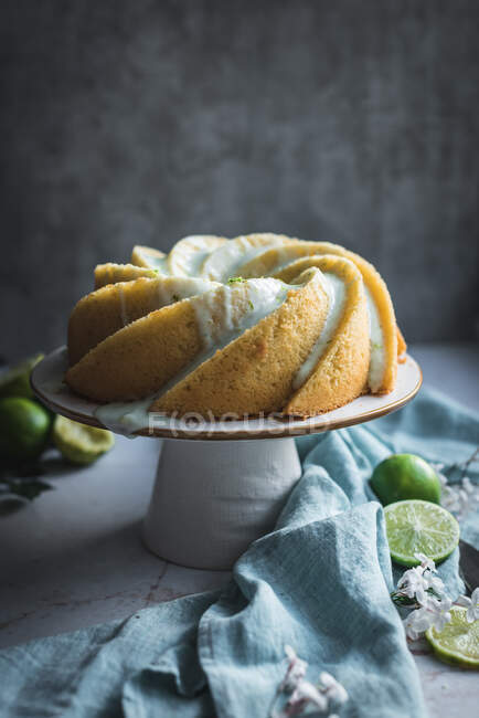 Gustoso pan di Spagna al lime servito su piatto bianco vicino a fiori e fette di lime — Foto stock