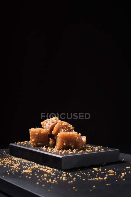 Gelatina di mele cotogne gourmet in piatto di ceramica cosparsa di semi di sesamo su fondo nero — Foto stock