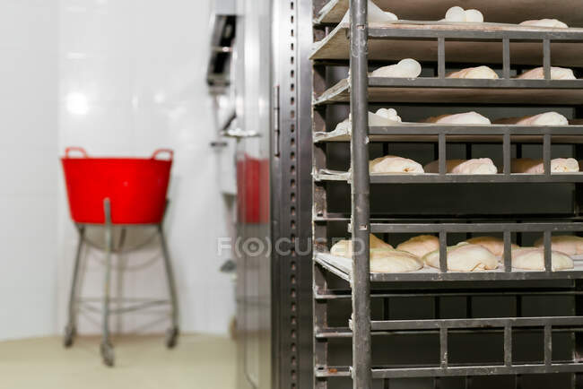 Металлическая стойка с мокасинами из теста помещена на кастрюли на кухне современной пекарни — стоковое фото