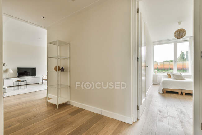 Heller Korridor mit Türen zum Wohnzimmer mit TV und Schlafzimmer mit bequemem Bett — Stockfoto