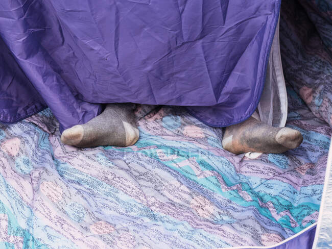 From above of unrecognizable traveler in socks resting in tent in daytime at campsite — Stock Photo