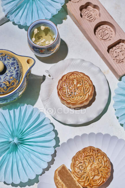 From above of traditional mooncakes with filling served on table with baking molds near kettle with herb tea in light room — Stock Photo
