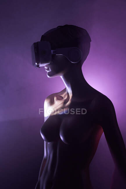 Жіночий дурень з VR-окулярами розміщений проти яскравого фіолетового фону як символ футуристичної технології — стокове фото