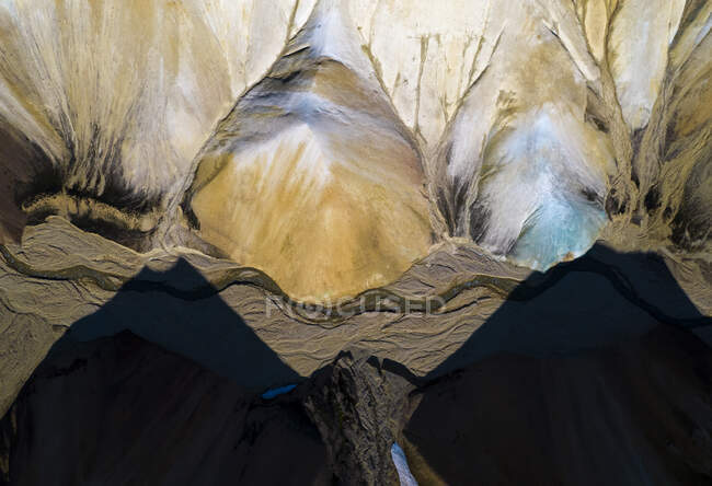 Вид беспилотника на грубые каменные образования с неровной поверхностью, расположенные под солнечным светом с тенями гор в природе Исландии — стоковое фото