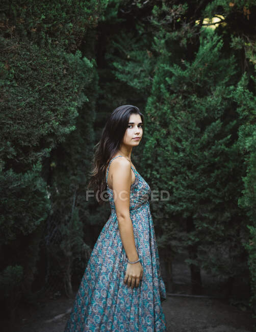 Seitenansicht einer schönen jungen Frau, die ihre Zeit in einem Garten genießt, während sie in die Kamera schaut — Stockfoto