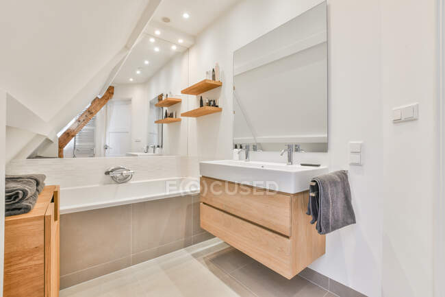 Interior do banheiro moderno com banheira e móveis de madeira em mansarda de casa espaçosa — Fotografia de Stock