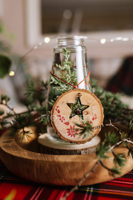 Ajuste de mesa de Navidad con corona y adornos decorativos de madera y mantel a cuadros rojo con luces amarillas en el fondo - foto de stock