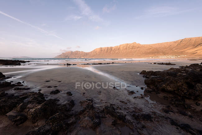 Scenic view of Famara Beach against mount and ocean under cloudy sky in Teguise Lanzarote Canary Islands Spain — Stock Photo