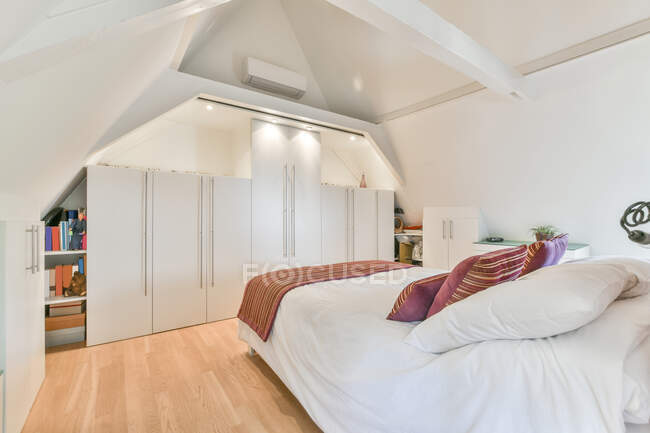 Cama macia confortável com linho branco e travesseiros coloridos no quarto elegante no apartamento moderno — Fotografia de Stock
