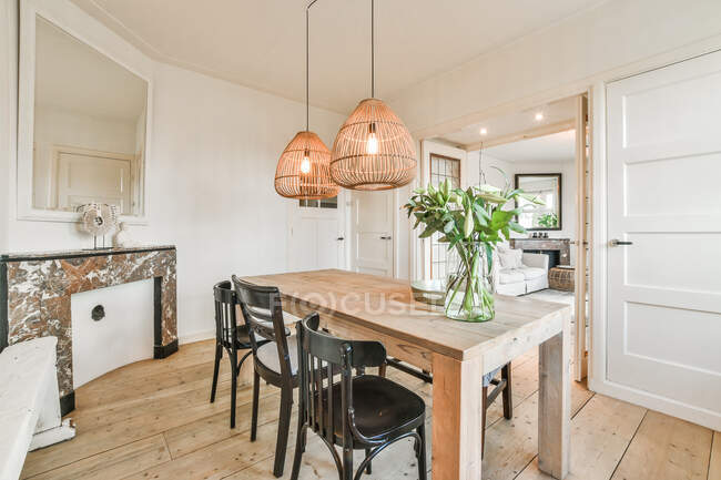 Design criativo da sala de jantar com banco e mesa de madeira sob lâmpadas penduradas em uma casa brilhante — Fotografia de Stock