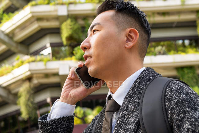 Молодой этнический предприниматель мужчина с галстуком с нетерпением ждем, выступая по мобильному телефону в городе — стоковое фото