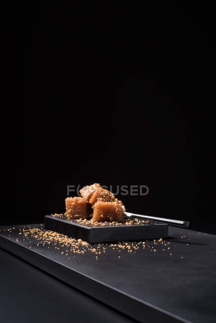 Gelatina di mele cotogne gourmet in piatto di ceramica cosparsa di semi di sesamo su fondo nero — Foto stock