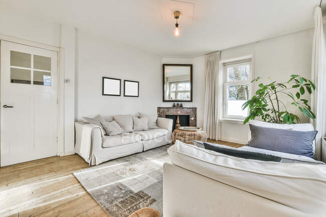 Soggiorno contemporaneo interno con tappeto tra divani con cuscini e plaid in casa luce — Foto stock