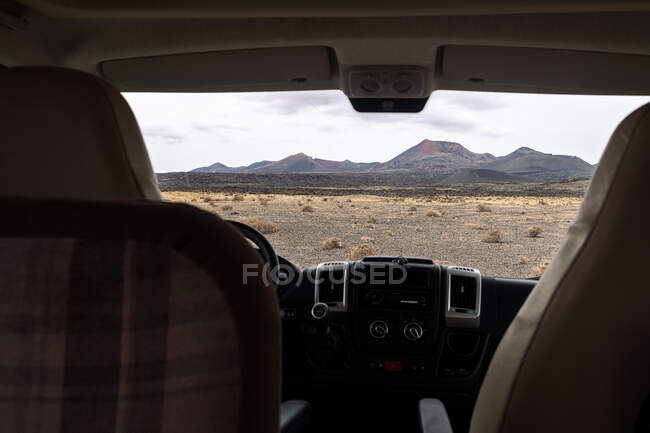 From inside vehicle view of volcano Cuervo and mount under cloudy sky in Tinajo Lanzarote Canary Islands Spain — Stock Photo
