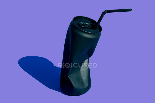 Чорна крихта порожня, що використовується баночка напою з соломою, розміщена на фіолетовому фоні в сучасній легкій творчій студії з тіні — стокове фото