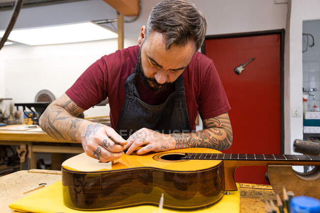 Luthier craftsman adjusting a classic guitar — Stock Photo