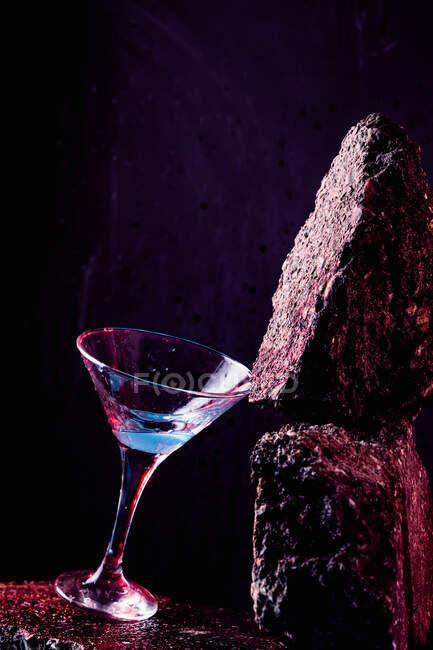 Glass of Blue Lagoon alcoholic cocktail placed on rough stone in bright studio — Stock Photo