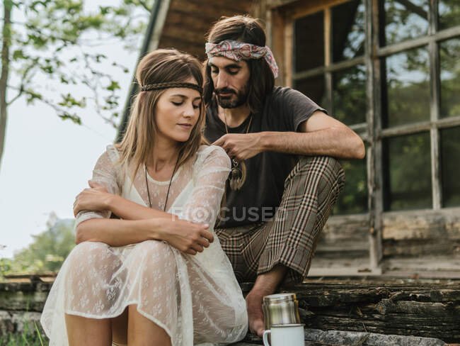 Attractive woman in a see-through dress looks away as her boyfriend braids her hair — Stock Photo