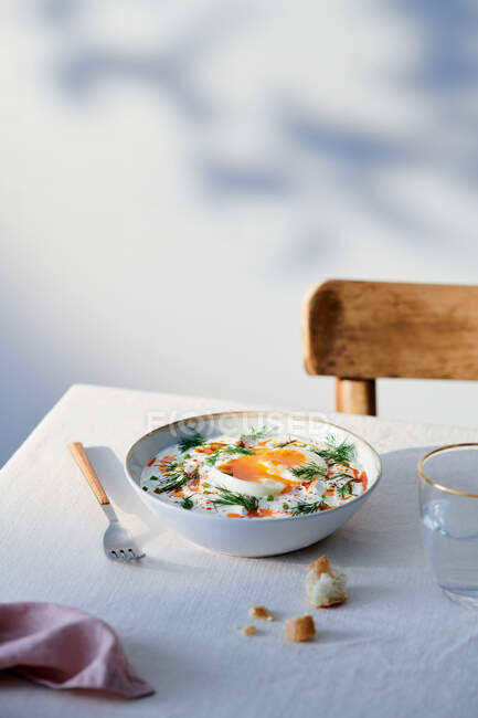 Hoher Winkel der Keramikschale mit türkischen Eiern auf dem Tisch neben Glas mit Wasser und Gabel — Stockfoto