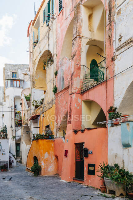 Authentic shabby colorful residential buildings buildings located on narrow paved street on island of Procida on sunny day — Stock Photo