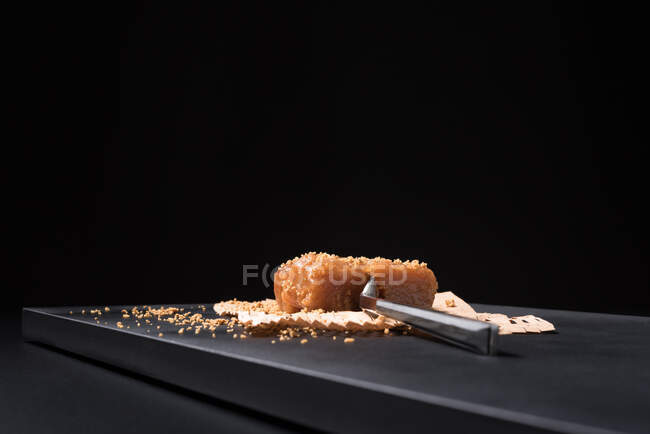 Pasta de geleia de marmelo gourmet em placa de cerâmica polvilhada com sementes de gergelim sobre fundo preto — Fotografia de Stock