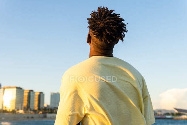 Back view of unrecognizable of calm African American male in casual clothes standing with closed eyes on street in summer — Stock Photo
