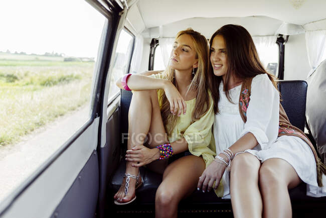 Zwei süße kaukasische Mädchen, die in Sommerkleidung in einem Lieferwagen sitzen und aus dem Fenster schauen — Stockfoto