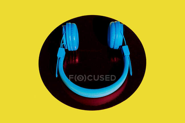 Vista superior de auriculares inalámbricos colocados en círculo sobre fondo amarillo - foto de stock