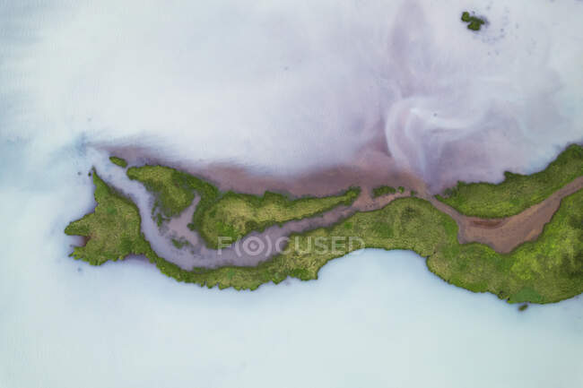 Drone vista di formazioni rocciose brune grezze circondate da lussureggianti piante verdi coperte da fitta nebbia nella natura dell'Islanda — Foto stock