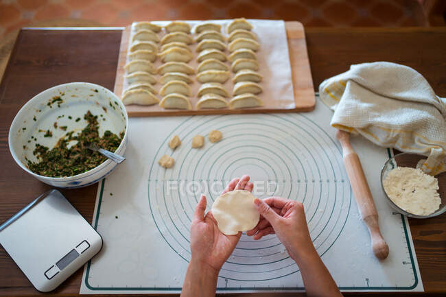 Dall'alto di raccolto anonimo femminile cuoco ripieno pasta con carne durante la preparazione di gnocchi tradizionali cinesi in cucina — Foto stock