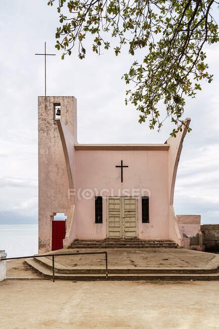 Фасад католической церкви установлен на острове Так Том и Прнсипи против голубого океана под облачным небом в дневное время — стоковое фото