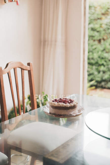 Смачний домашній торт, прикрашений ягодами та вершками, поміщений на скляний стіл — стокове фото