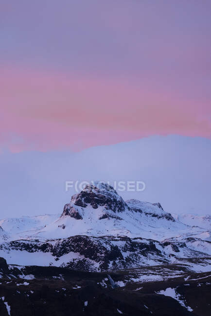 Живописный пейзаж скалистых гор со снежными вершинами против удивительного розового заката неба в Исландии — стоковое фото