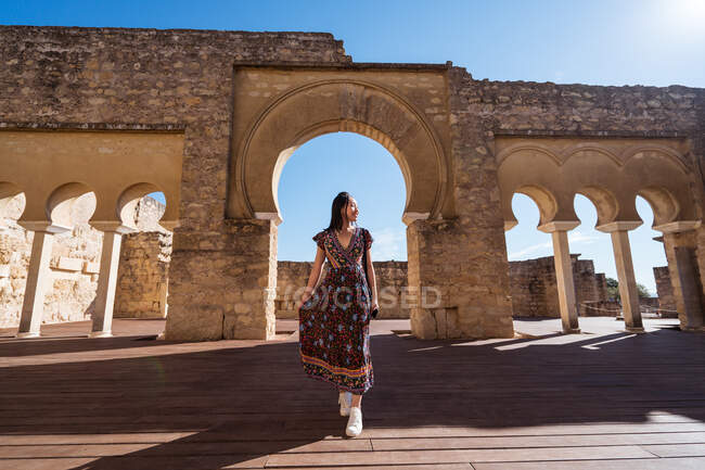Ganzkörper einer asiatischen Reisenden, die in der Nähe eines steinernen antiken Portikus mit Säulen und gewölbten Passagen während ihrer Reise in Cordoba steht — Stockfoto