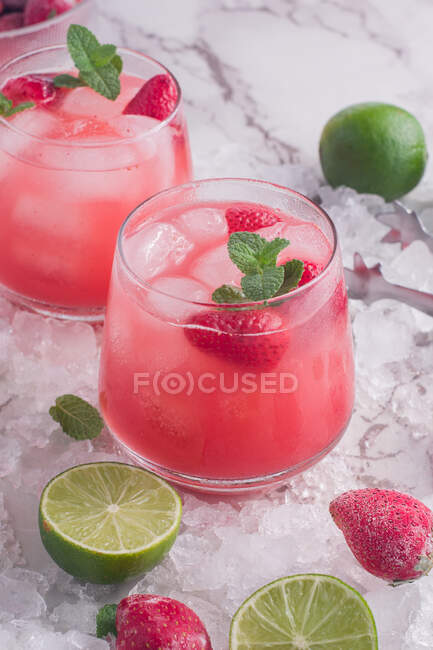 From above of glasses of cold coconut water with strawberries served on ice background — Stock Photo