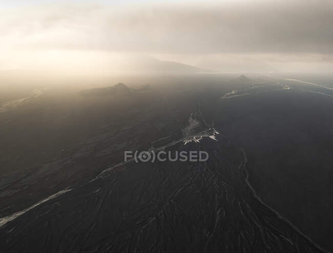 Drone view of narrow brook flowing through mountainous terrain in gloomy weather against cloudy sky in wild nature of Iceland — Stock Photo