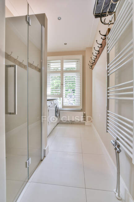 Interno del bagno illuminato dal sole con cabina doccia e stendino contro finestra in appartamento moderno — Foto stock