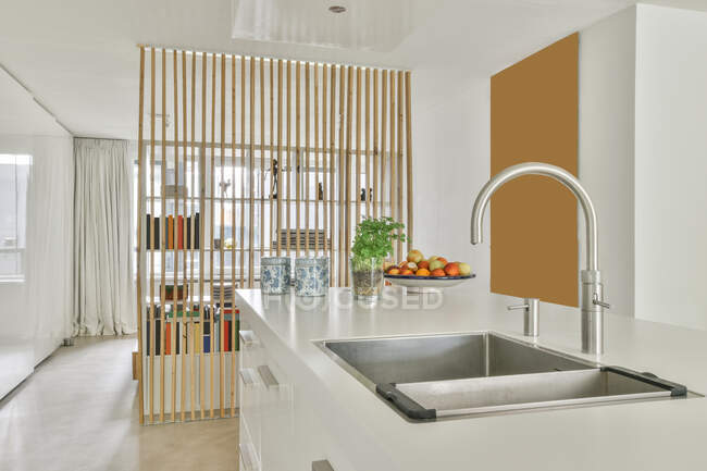 Interior de la cocina contemporánea con grifo de acero inoxidable contra frutas frescas en la placa en la casa de luz - foto de stock