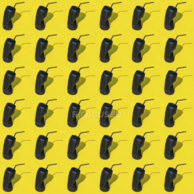 Boite de boisson vide froissée noire avec paille placée sur fond jaune dans un studio créatif moderne et lumineux avec ombre — Photo de stock