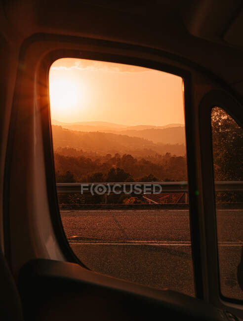 Breathtaking scenery through opened car window of orange sundown over highlands in Galicia — Stock Photo