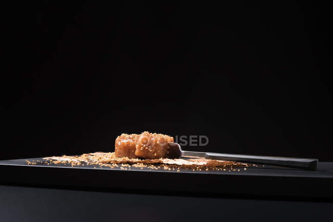 Жирна паста з желе в керамічній тарілці, посипана насінням кунжуту на чорному фоні — стокове фото