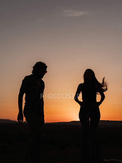 Siluetas de una pareja bailando en la naturaleza mientras el sol se esconde en las montañas - foto de stock