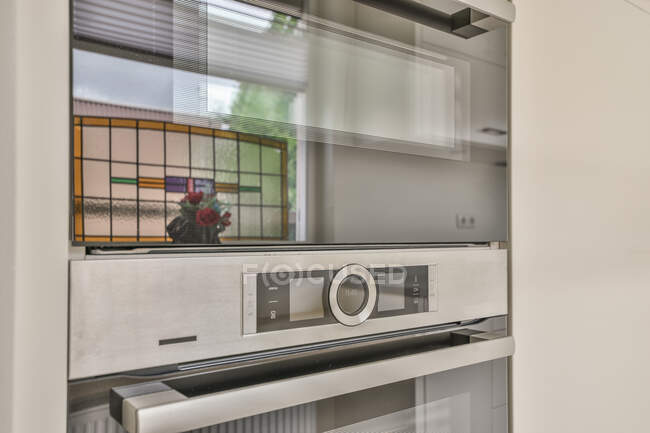 Kreatives Design der eingebauten Mikrowelle und Bedienfeld des Ofens reflektiert blühende Blumen zu Hause — Stockfoto