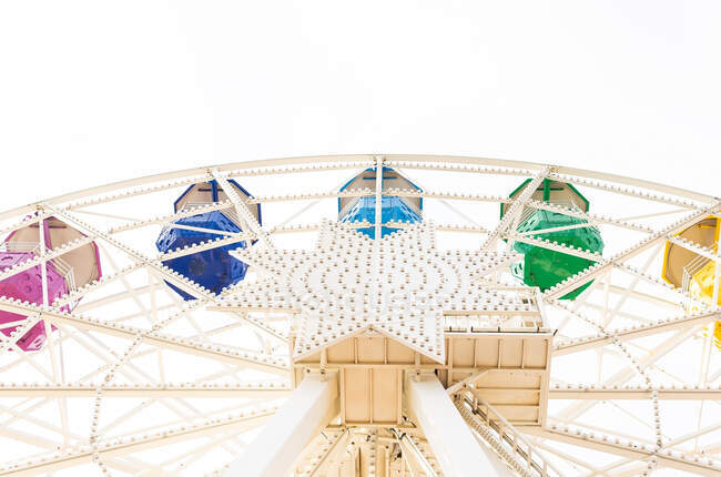 Round public observation wheel with multicolored passenger cabins against clear sky in amusement park — Stock Photo