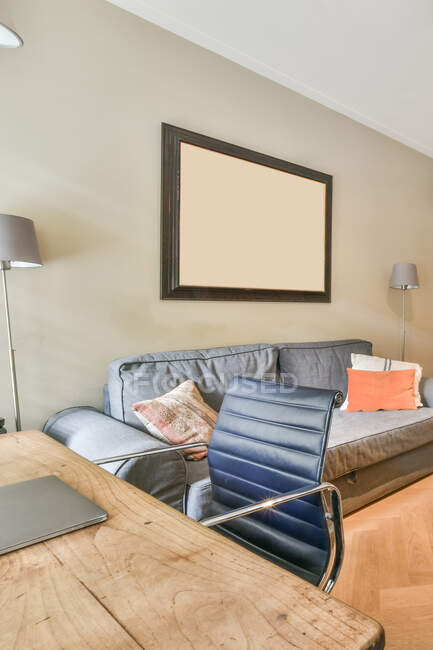 Soggiorno contemporaneo interno con divano contro poltrona e netbook su scrivania in legno in casa — Foto stock