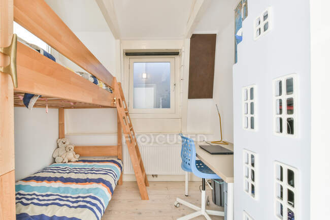 Quarto moderno para crianças decorado com beliche de madeira perto da mesa e cadeira azul no apartamento — Fotografia de Stock