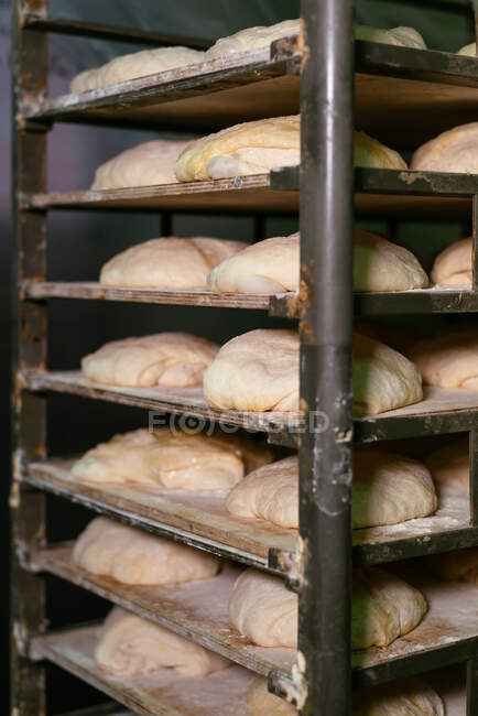 Pieces of bread raw dough placed on metal rack in kitchen of bakehouse — Stock Photo